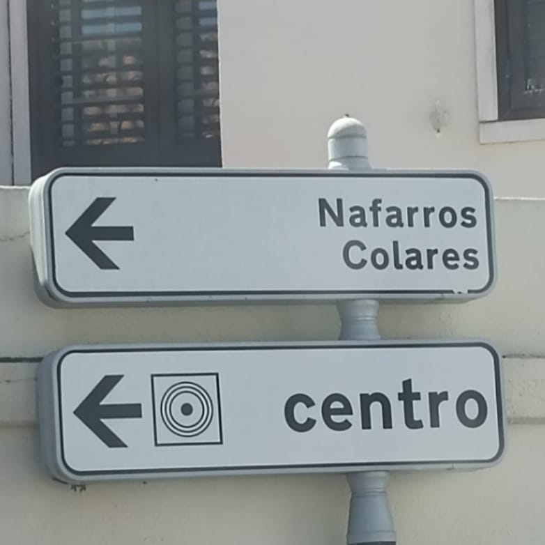 A Portuguese road sign pointing left towards Nafarros and Colares
