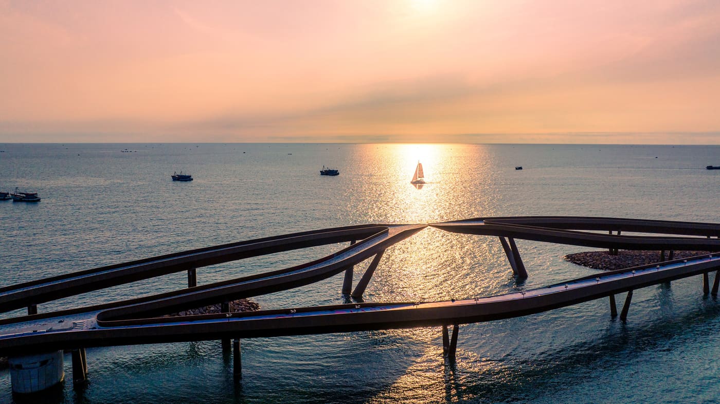 The Kiss Bridge at sunset on Phú Quốc, its two halves reaching towards each other over the sea without touching