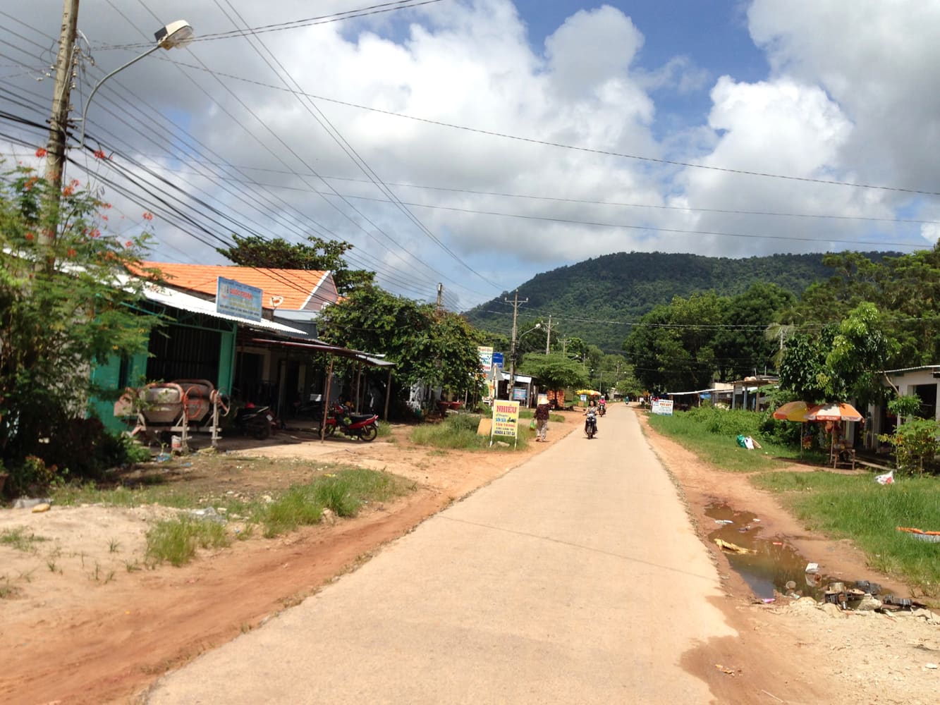 A road on Phú Quốc island with motorbikes and roadside shops